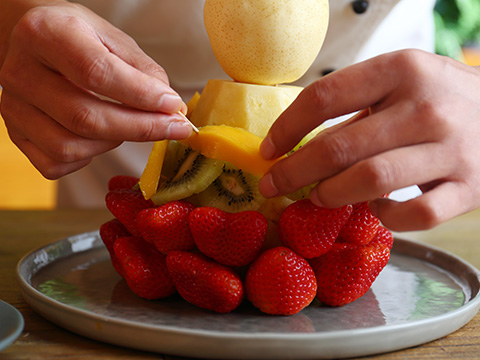 用牙签把所有的水果一层层插在菠萝的上面。